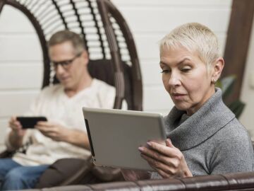 Un hombre y una mujer con dispositivos electr&oacute;nicos