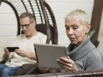 Un hombre y una mujer con dispositivos electrónicos Un hombre y una mujer con dispositivos electrónicos