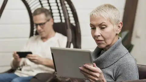 Un hombre y una mujer con dispositivos electrónicos Un hombre y una mujer con dispositivos electrónicos