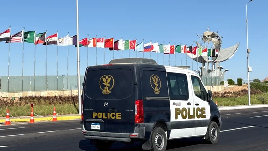 Un vehículo policial pasa junto a las banderas de los países participantes en la cumbre para celebrar la firma del acuerdo de alto el fuego entre Israel y Hamás. Un vehículo policial pasa junto a las banderas de los países participantes en la cumbre para celebrar la firma del acuerdo de alto el fuego entre Israel y Hamás.