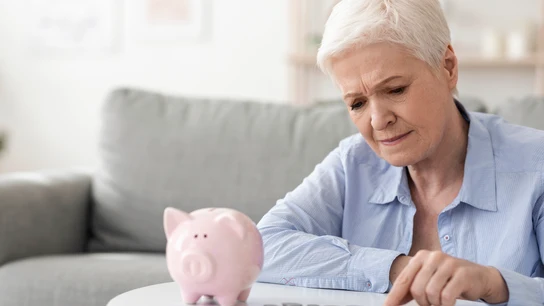 Mujer mayor contando dinero de una hucha Mujer mayor contando dinero de una hucha