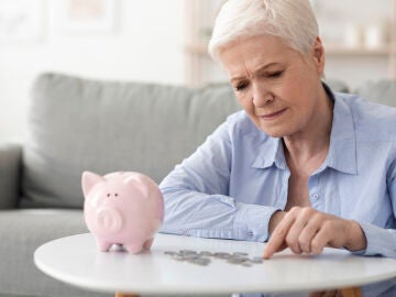 Mujer mayor contando dinero de una hucha