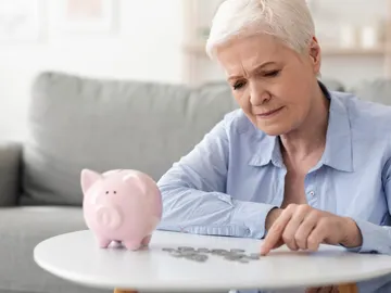 Mujer mayor contando dinero de una hucha Mujer mayor contando dinero de una hucha