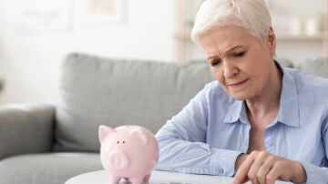 Mujer mayor contando dinero de una hucha