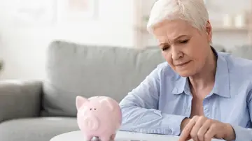 Mujer mayor contando dinero de una hucha Mujer mayor contando dinero de una hucha