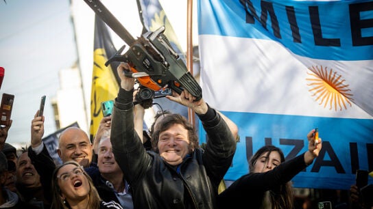Javier Milei alza una motosierra frente a la bandera argentina en 2023.