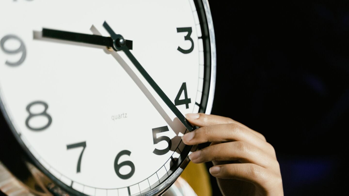 Una persona manipulando las agujas de un reloj