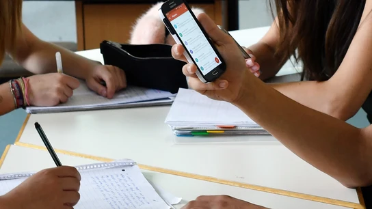 Un joven utilizando un teléfono móvil en clase Un joven utilizando un teléfono móvil en clase