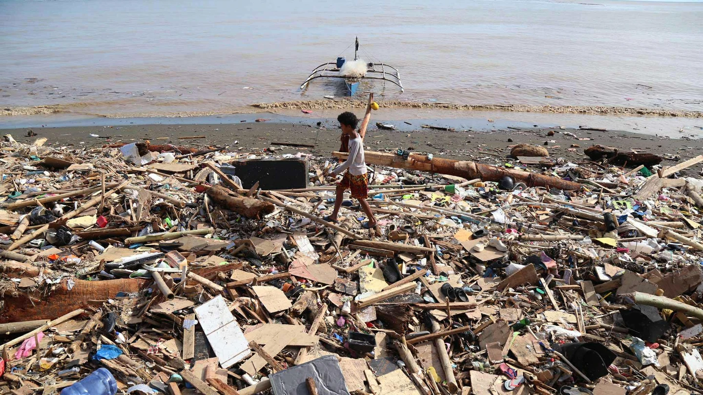 Un joven camina entre los escombros que deja el paso del tifón Kilmaegi en Filipinas Un joven camina entre los escombros que deja el paso del tifón Kilmaegi en Filipinas