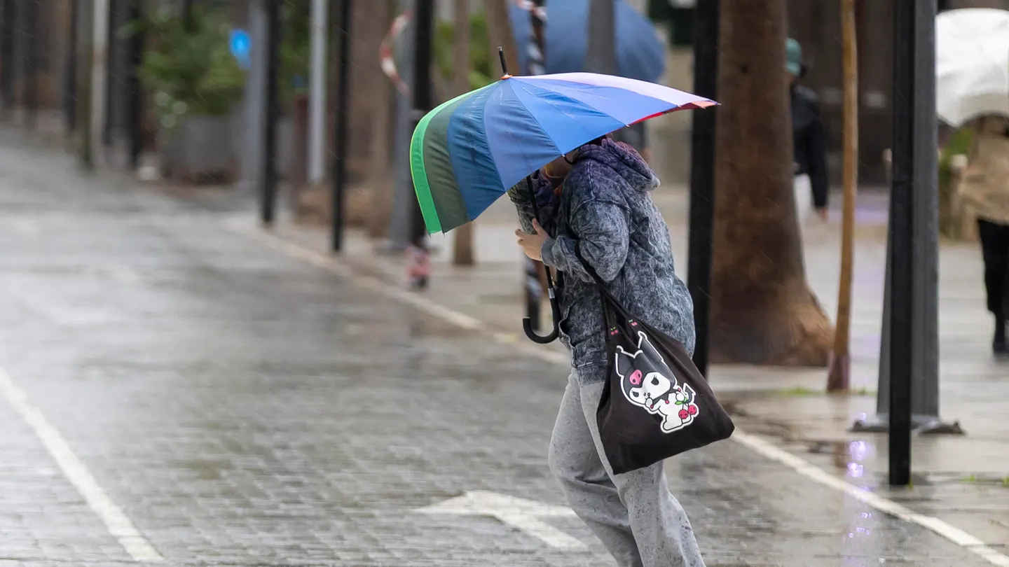 Una mujer se protege de la lluvia y del viento en Huelva Una mujer se protege de la lluvia y del viento de la borrasca Claudia en Huelva