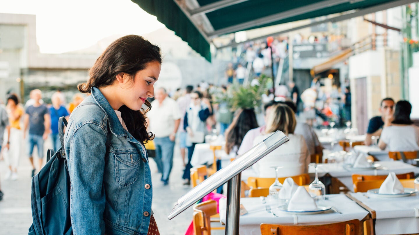 Chica mirando el men&uacute; de un restaurante