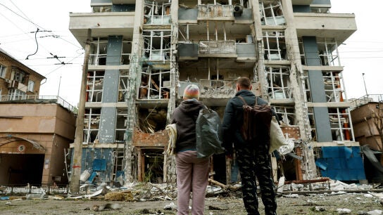 Imagen de archivo de mayo de 2025 de dos personas contemplando los destrozos provocados por un ataque ruso en un edificio residencial de Kyiv
