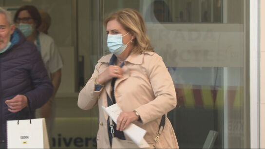 Una mujer a la salida de un hospital portando una mascarilla