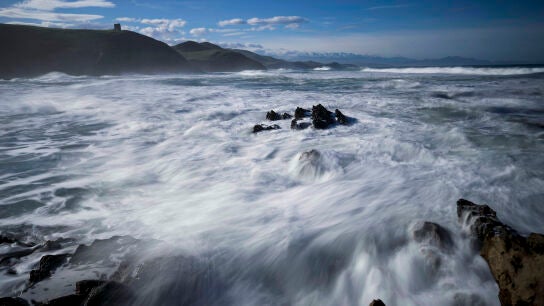 Oleaje, este jueves, en la playa de la localidad c&aacute;ntabra de Tagle con los Picos de Europa al fondo
