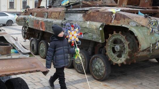 Un ni&ntilde;o ucraniano sostiene una estrella de Bel&eacute;n en la exposici&oacute;n callejera de equipo militar ruso destruido cerca de la Catedral de San Mykhailivsky en Kyiv este 25 de diciembre, durante las celebraciones navide&ntilde;as en medio de la invasi&oacute;n rusa.