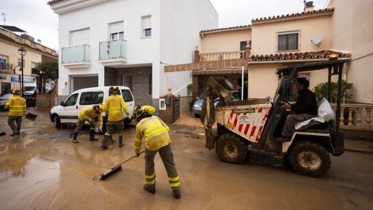 Efectivos de Infoca colaboran en las labores de limpieza de las calles este domingo en Estaci&oacute;n de C&aacute;rtama despu&eacute;s de los problemas sufridos anoche en la localidad por la crecida del r&iacute;o Guadalhorce