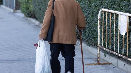 Una persona mayor camina con ayuda de un bast&oacute;n.