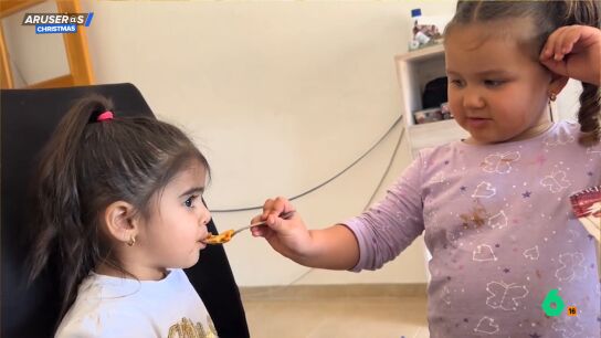 Una ni&ntilde;a da de comer a su hermana peque&ntilde;a