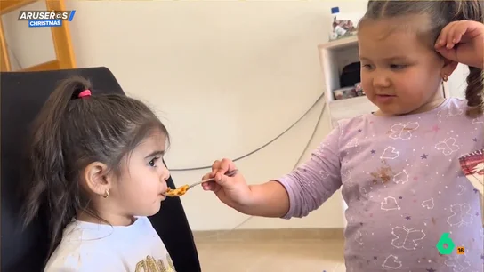 Una niña da de comer a su hermana pequeña Una niña da de comer a su hermana pequeña