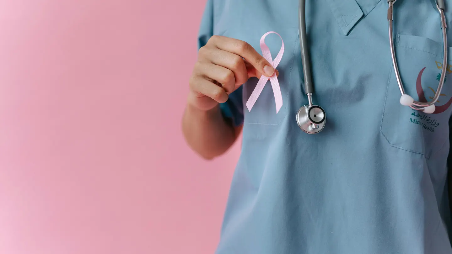 Primer plano de una mano sujetando un lazo rosa, símbolo del cáncer de mama. Primer plano de una mano sujetando un lazo rosa, símbolo del cáncer de mama.