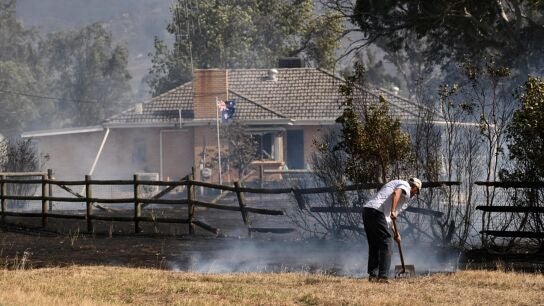 Un hombre cerca de una propiedad rodeada de tierra quemada en Longwood, Victoria, Australia. 