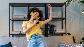 Mujer joven escuchando y cantando una canci&oacute;n