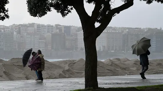 Varias personas se protegen de la lluvia junto a la costa de A Coruña este miércoles Varias personas se protegen de la lluvia junto a la costa de A Coruña este miércoles