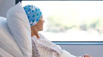 Mujer enferma de cáncer, en la cama de un hospital mirando por la ventana Mujer enferma de cáncer, en la cama de un hospital mirando por la ventana