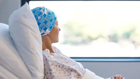 Mujer enferma de cáncer, en la cama de un hospital mirando por la ventana Mujer enferma de cáncer, en la cama de un hospital mirando por la ventana