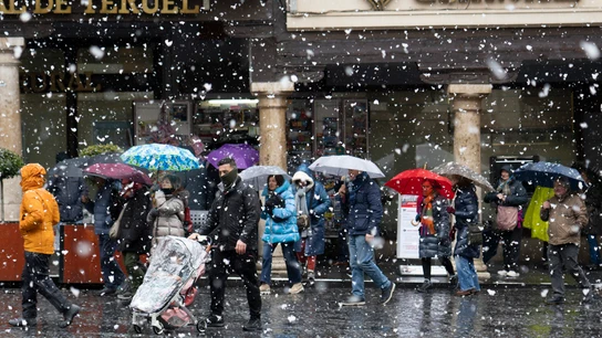 Varias personas caminan por una calle de Teruel durante la nevada por la borrasca Kristin Varias personas caminan por una calle de Teruel durante la nevada por la borrasca Kristin