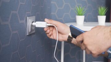 Persona enchufando el cargador a la pared