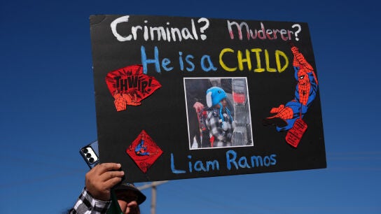 Un hombre protesta contra el ICE con la foto de Liam Ramos. 