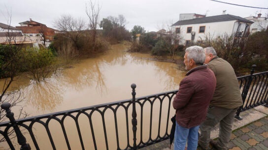 Dos personas, ante la crecida de un r&iacute;o
