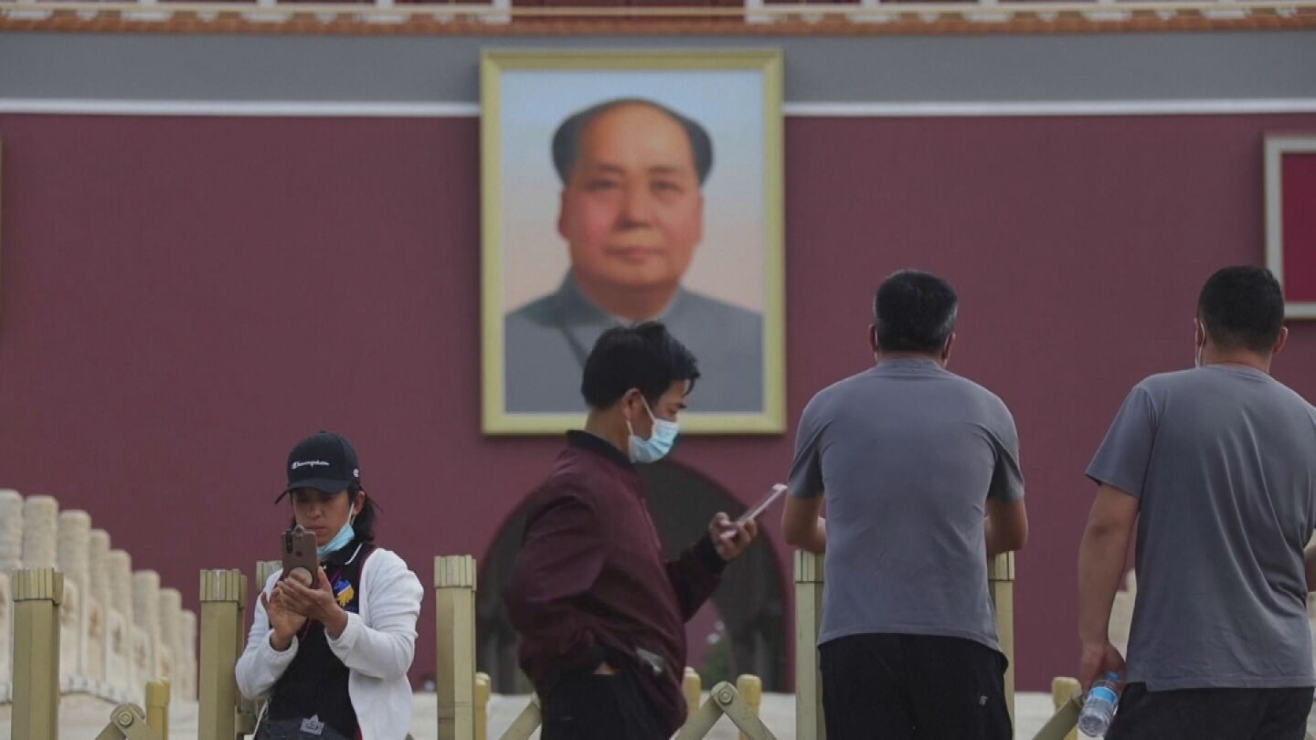 Un joven mira su tel&eacute;fono bajo la mirada de Mao en Tiananmen, en Pek&iacute;n.