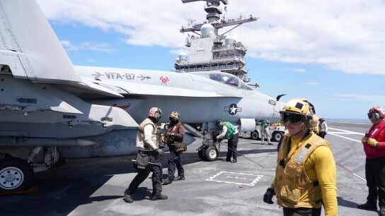 Un oficial de catapulta, a la derecha, pasa junto a un F-18 Super Hornet en la cubierta de vuelo del portaaviones USS Gerald R. Ford durante ejercicios militares en el Mediterr&aacute;neo