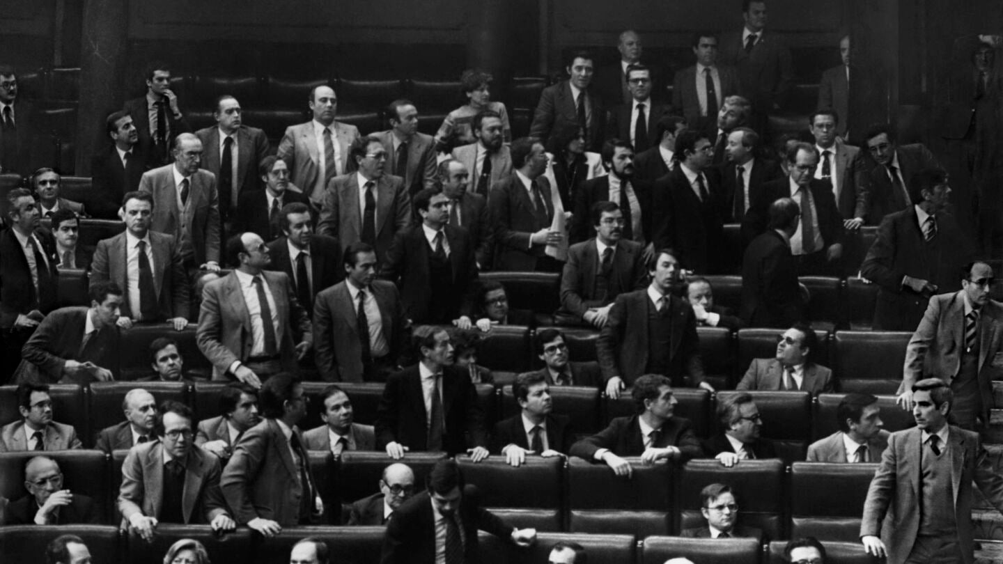 Los diputados se levantan de sus escaños y miran hacia la puerta por la que el teniente coronel de la Guardia Civil Antonio Tejero, pistola en mano, acaba de irrumpir en el Hemiciclo durante la segunda votación de investidura de Leopoldo Calvo Sotelo como presidente del Gobierno. 