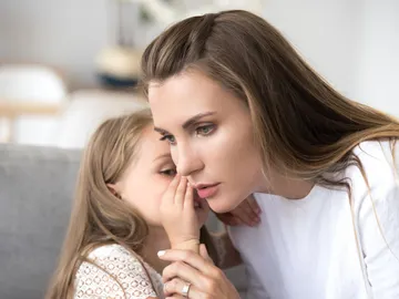 Una niña contándole un secreto a un adulto Una niña contándole un secreto a un adulto