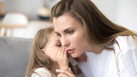 Una niña contándole un secreto a un adulto Una niña contándole un secreto a un adulto