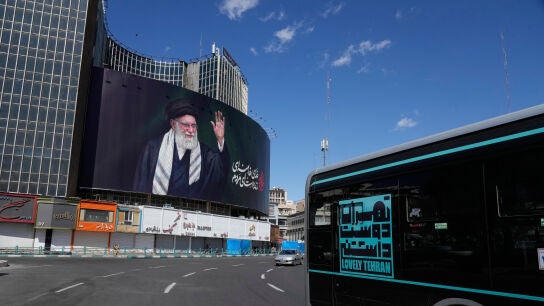 Veh&iacute;culos pasan junto a una valla publicitaria que muestra un retrato del difunto l&iacute;der supremo iran&iacute;, el ayatol&aacute; Al&iacute; Jamenei