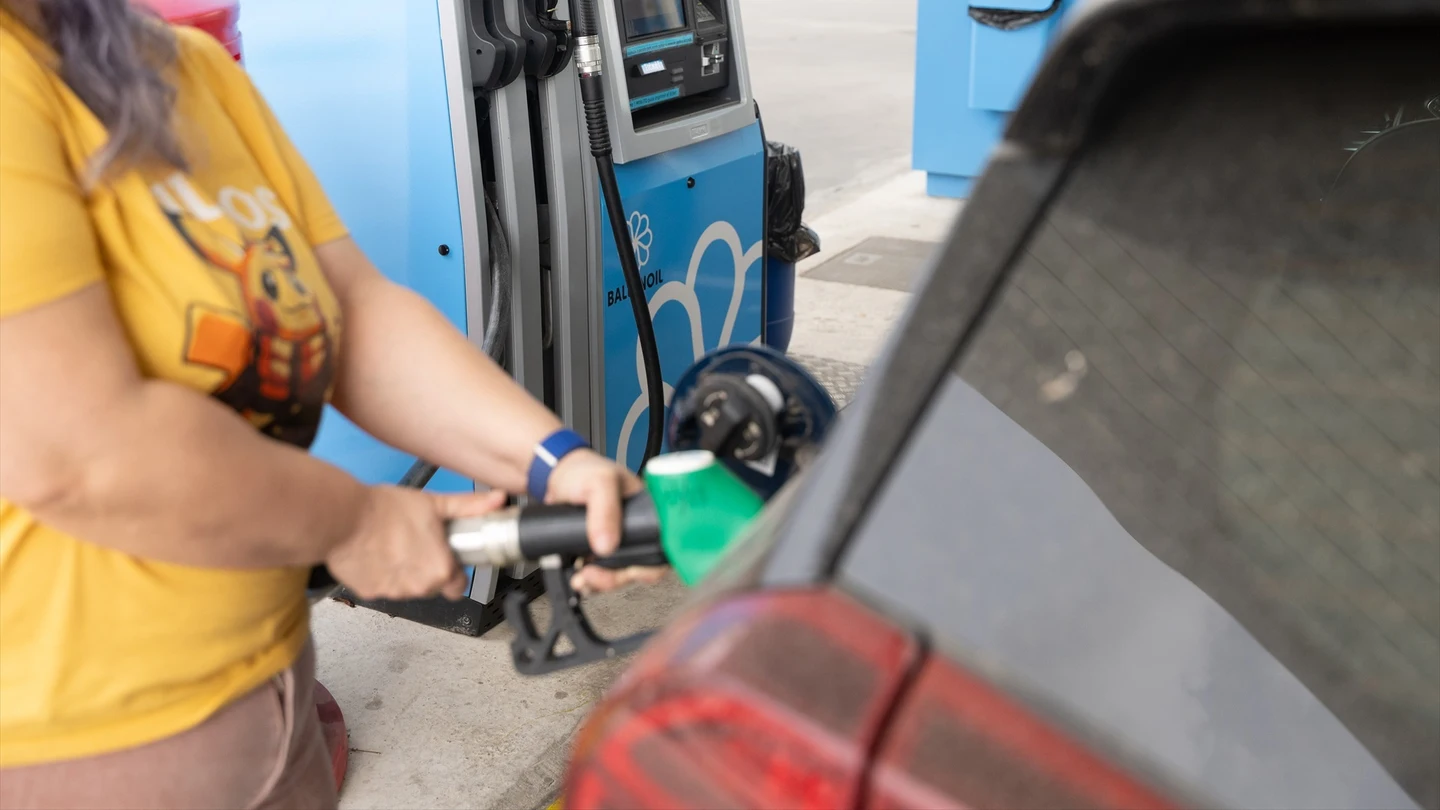 Una mujer reposta su coche en una gasolinera Una mujer reposta su coche en una gasolinera
