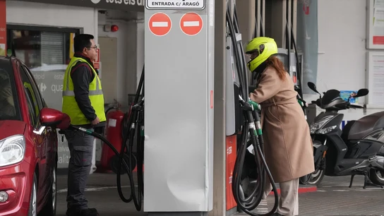 Una mujer repostando en una gasolinera Una mujer repostando en una gasolinera
