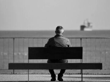 Un hombre sentado en un banco mirando al mar