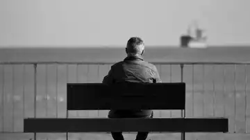 Un hombre sentado en un banco mirando al mar Un hombre sentado en un banco mirando al mar