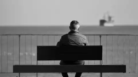 Un hombre sentado en un banco mirando al mar Un hombre sentado en un banco mirando al mar