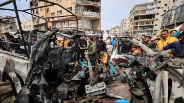 Palestinos inspeccionan los da&ntilde;os tras un ataque israel&iacute; contra un veh&iacute;culo policial en la ciudad de Gaza