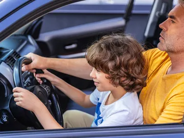 Padre dando lecciones de conducir (coche parado) a su hijo. Padre dando lecciones de conducir (coche parado) a su hijo.