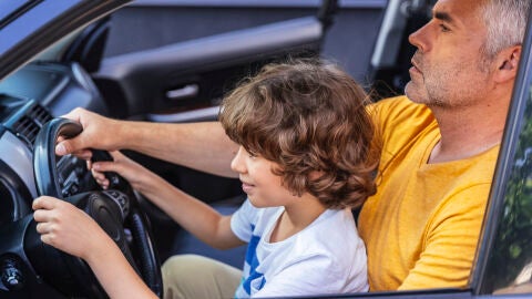 Padre dando lecciones de conducir (coche parado) a su hijo.