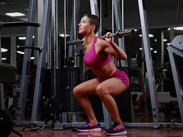 Mujer haciendo sentadillas en el gimnasio Mujer haciendo sentadillas en el gimnasio