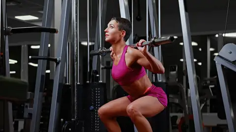 Mujer haciendo sentadillas en el gimnasio Mujer haciendo sentadillas en el gimnasio