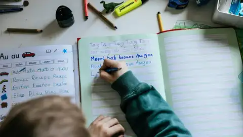 Un niño escribiendo en un cuaderno Un niño escribiendo en un cuaderno